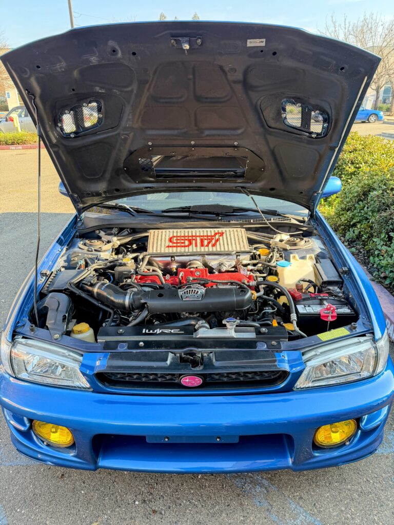 Subaru vehicle with hood open, showing engine