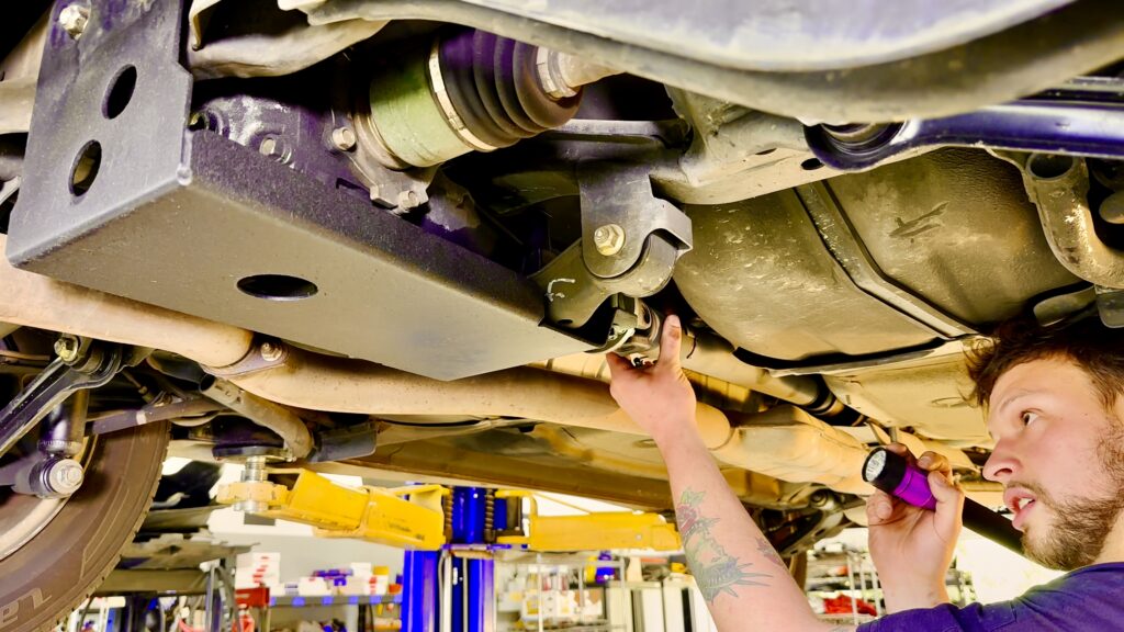 Subaru service technician inspecting a drive shaft